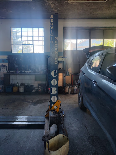 Interior del taller Cobos Servicio Mecánico en Bariloche — vehículo en elevador con el cartel del taller al fondo